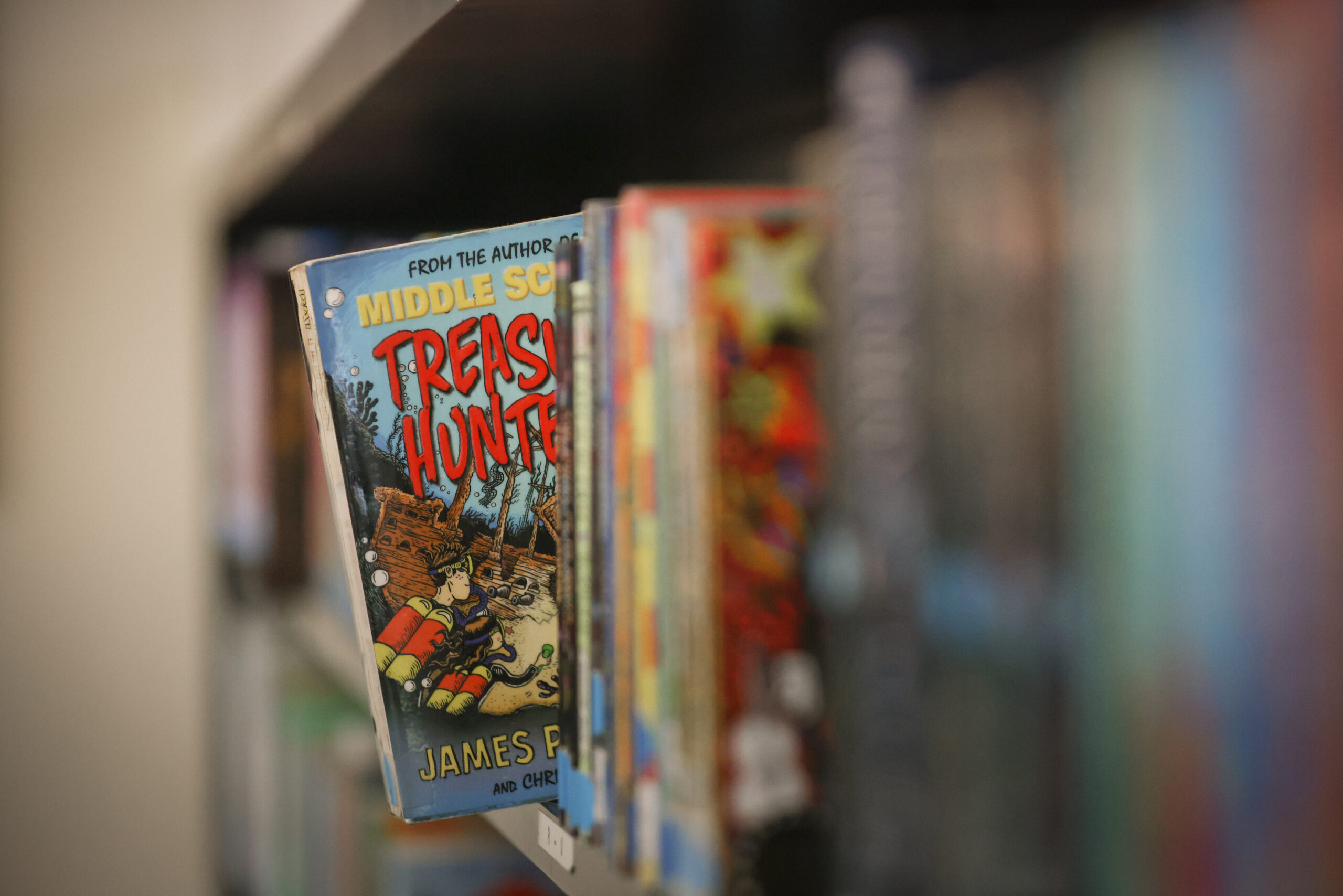 A shelf of books out of focus with one book leaning out in focus