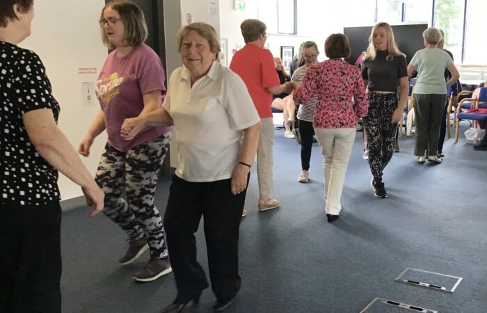 People céilí dancing and smiling.